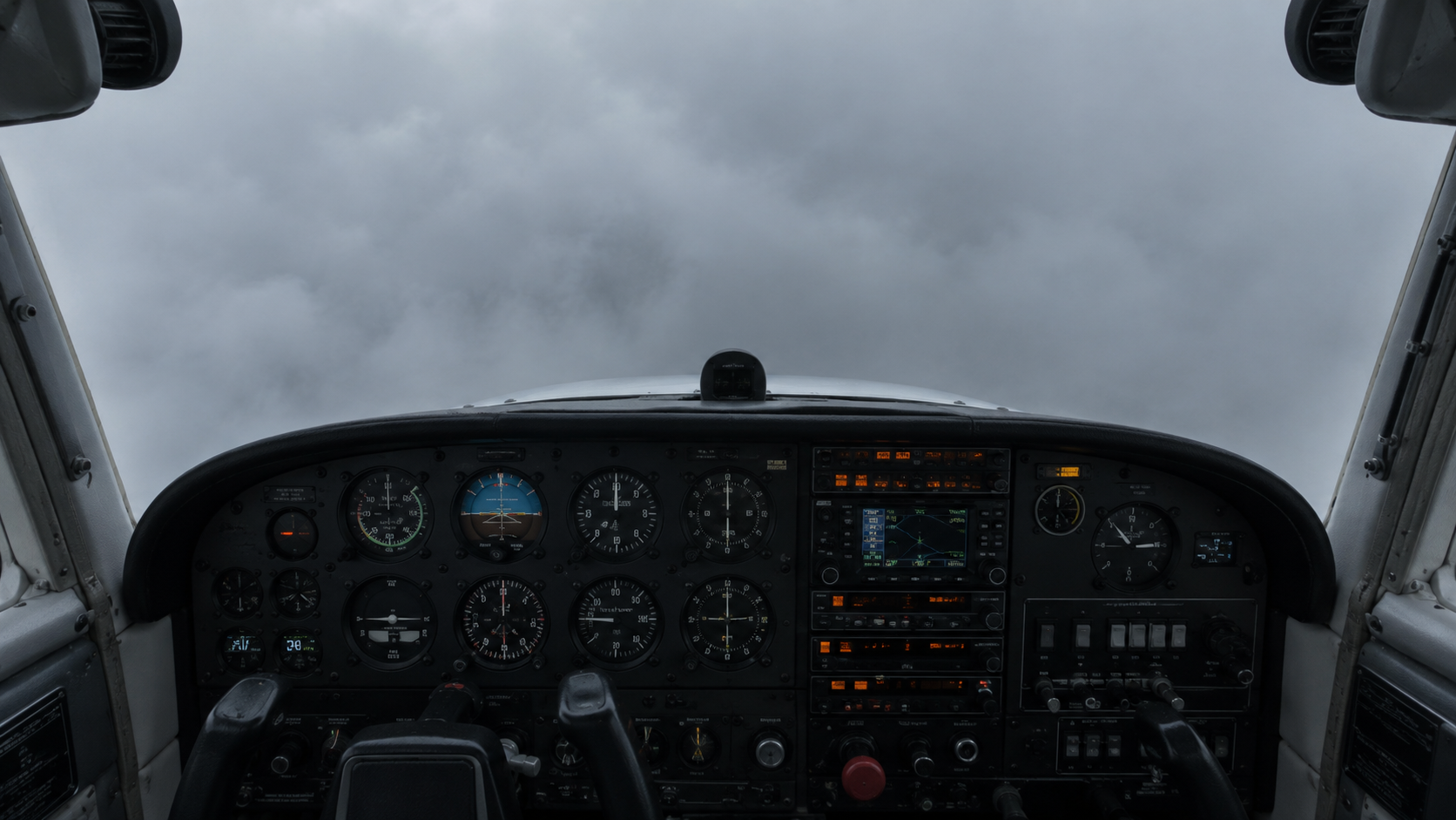 Pilot's view of aircraft instrument panel with artificial horizon, altimeter, and avionics displays under overcast sky through windscreen.